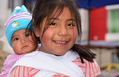 in der historischen Innensatdt von Quito tägt Mädchen ihre kleine Schwester auf dem Rücken
